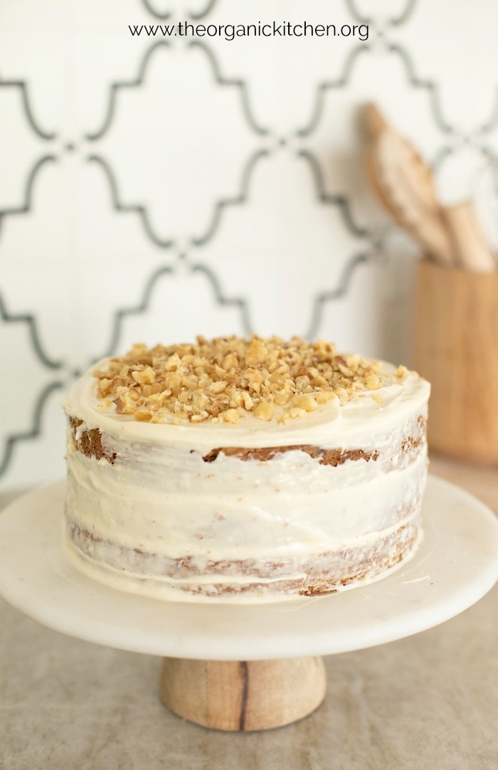 Carrot Cake with Cream Cheese Frosting garnished with chopped walnuts on cake plate