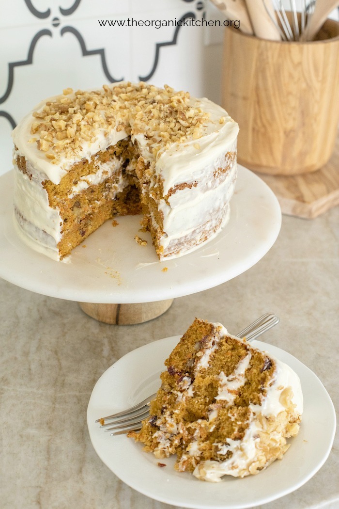 Carrot Cake with Cream Cheese Frosting on a cake plate with a slice of cake next to it