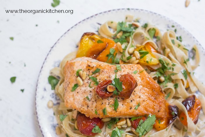 A single piece of Crispy Salmon with Blistered Tomatoes and Pasta on a white and blue plate