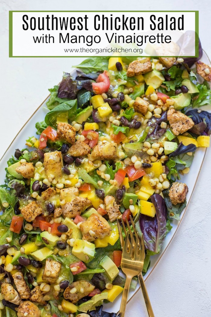 A close of of a platter with Southwest Chicken Salad with mango Vinaigrette with two gold forks