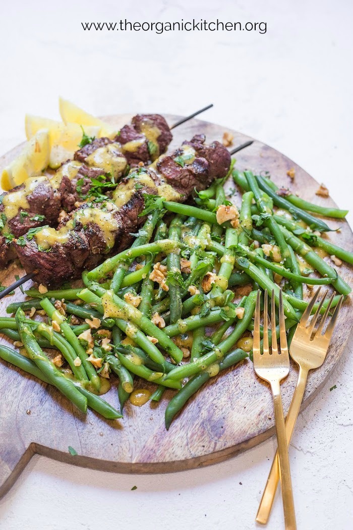 Steak Kabobs with Dijon Green Beans on platter set on white surface