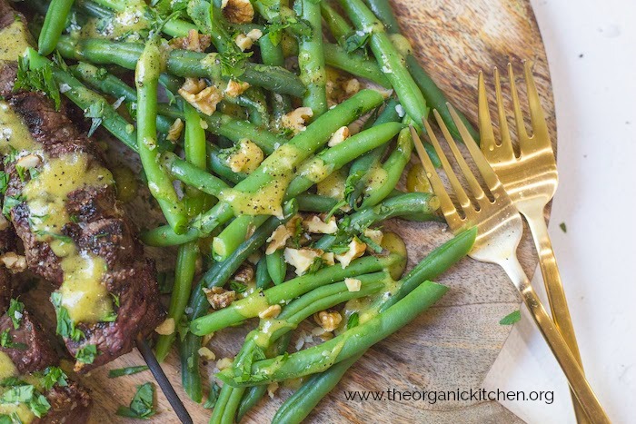 Steak Kabobs with Dijon Green Beans on wood platter with two gold forks