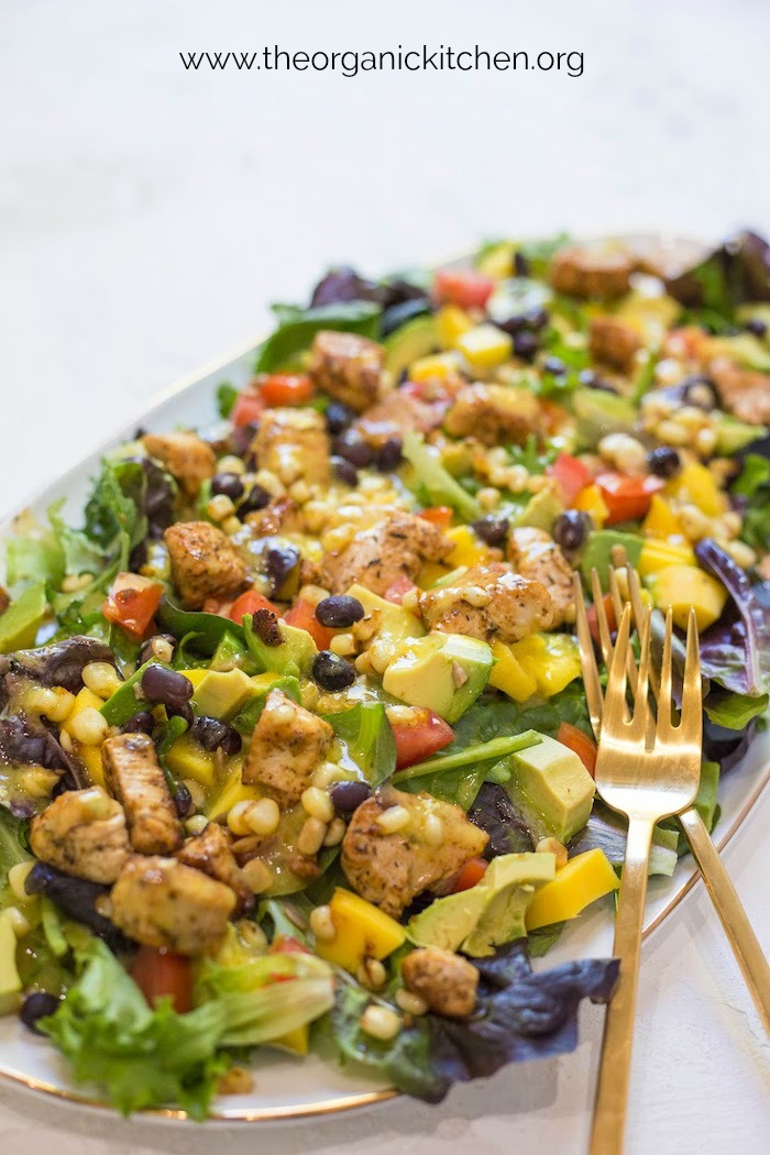 A close up of the Southwest Chicken Salad with Mango Vinaigrette on a gold trimmed platter with two gold fork with