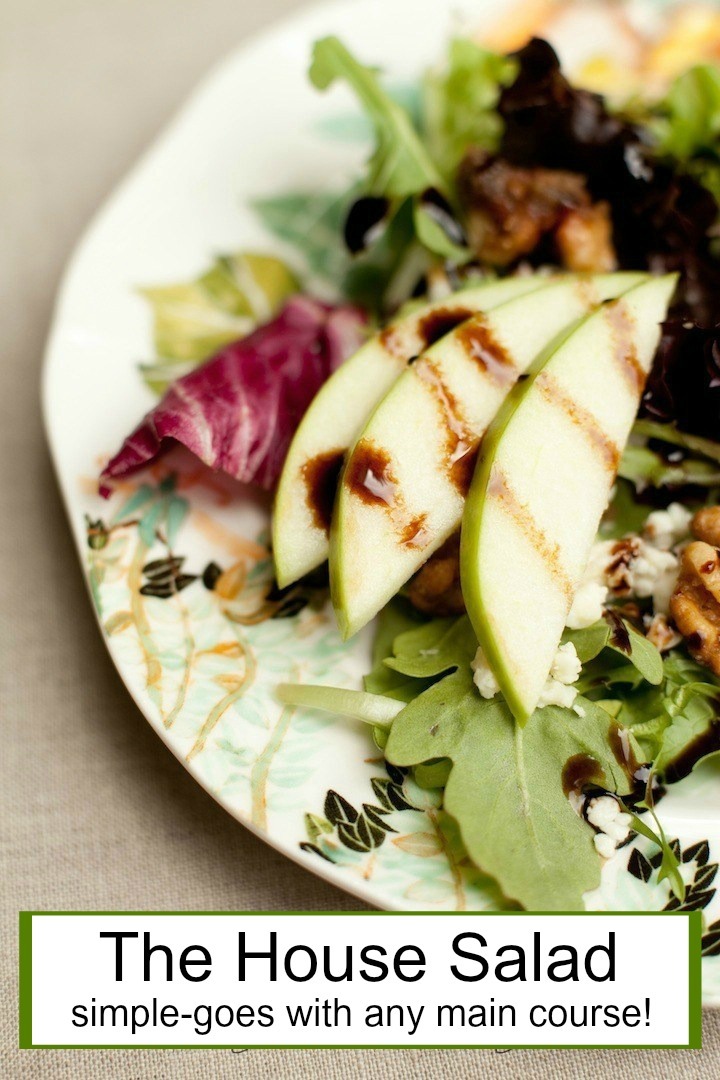 The Organic Kitchen 'House Salad', a close up of baby greens, sliced apple, caramelized nuts and feta cheese drizzled with balsamic vinaigrette on a white plate set on beige table cloth