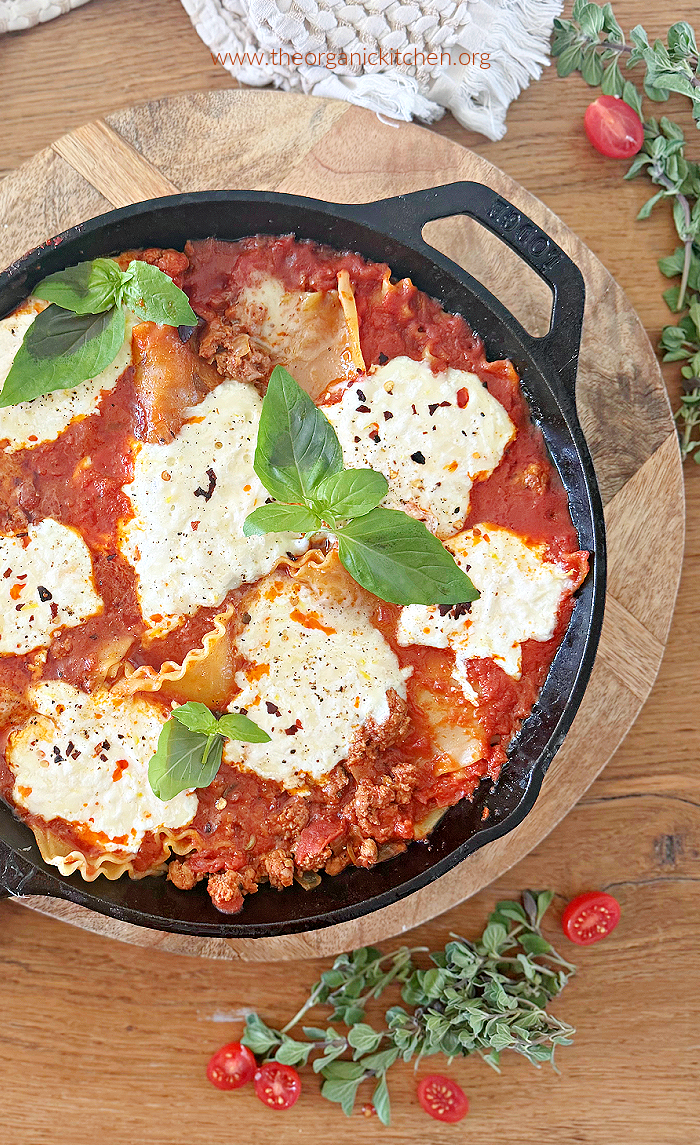 Stove Top Skillet Lasagna garnished with basil in black pan on wood table