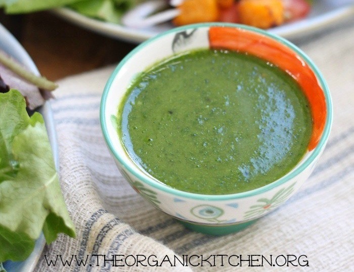 A bowl of green salad dressing to be used on Easy Caprese Salad with Pesto Vinaigrette