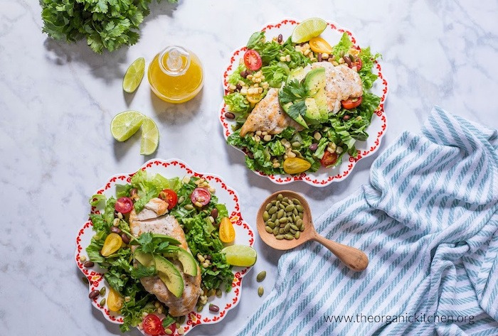 Two plates of Southwest Chicken Salad with Citrus Vinaigrette with lime wedges and pumpkin seeds