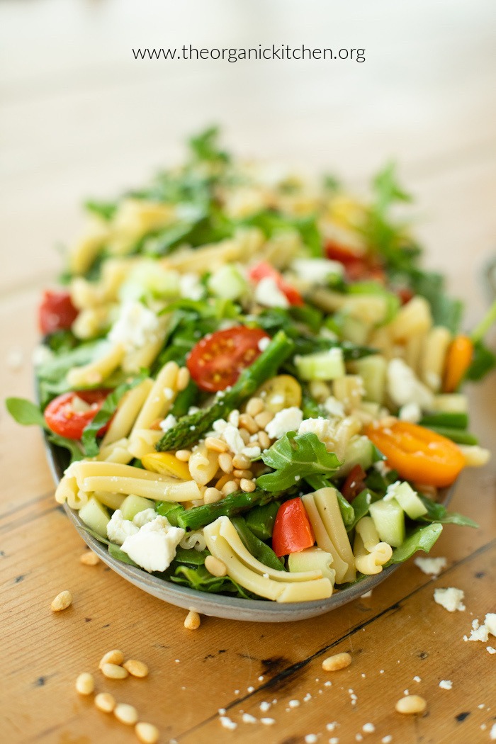 A platter of Pasta Salad with Greens and Asparagus on a pine table