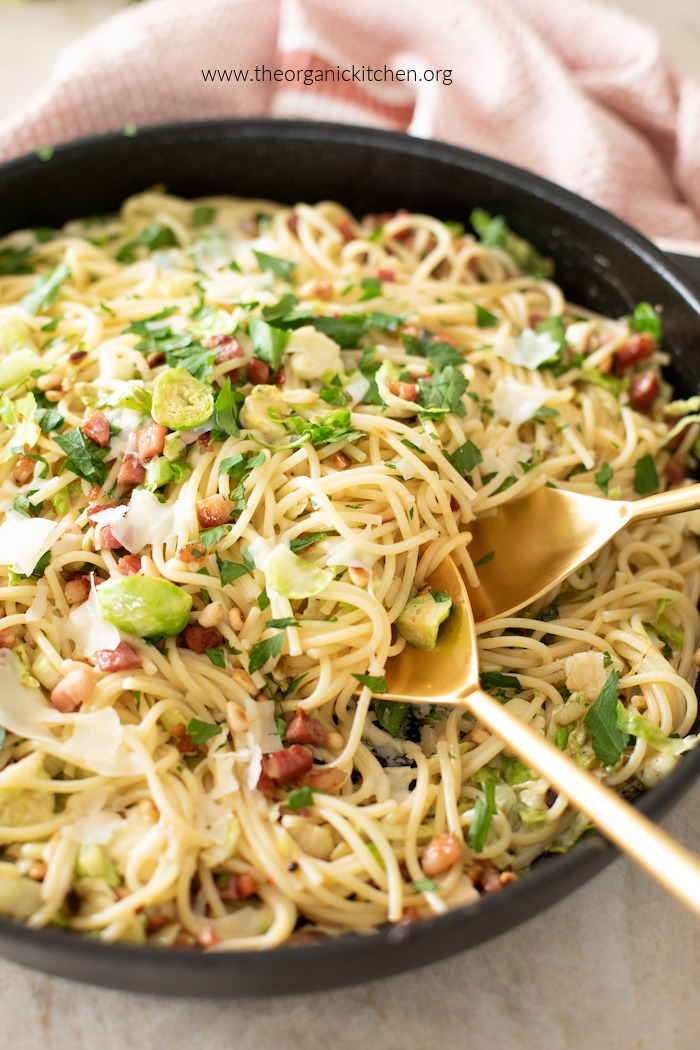Pasta with Brussels Sprouts and Pancetta in black skillet with gold serving spoons