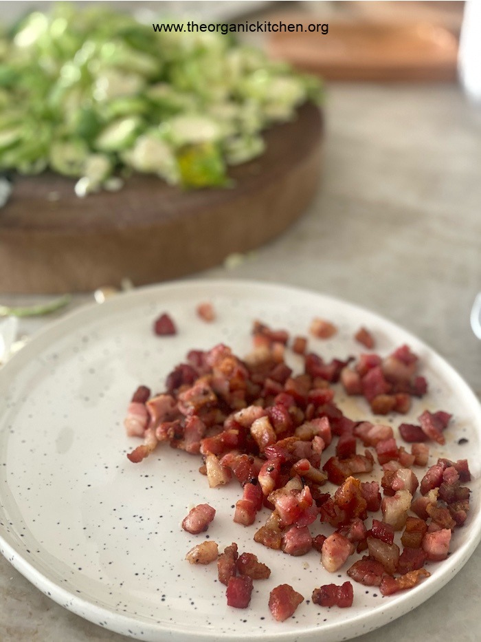 A cutting board with sliced brussels sprouts and a plate full of chopped pancetta for Pasta with Brussels Sprouts and Pancetta