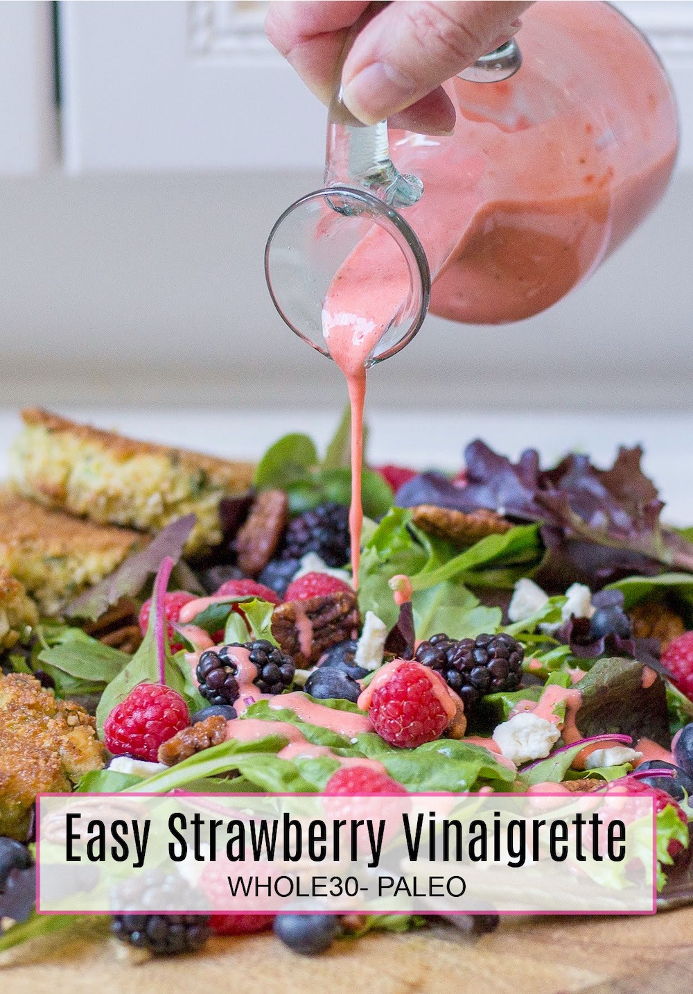 Creamy Strawberry Vinaigrette - Whole30/Paleo being poured onto a green salad on wood serving board