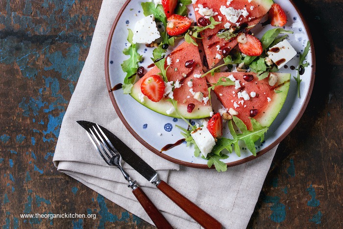 Easy watermelon salad on blue plate set on a beige napkin, serving utensils on the side