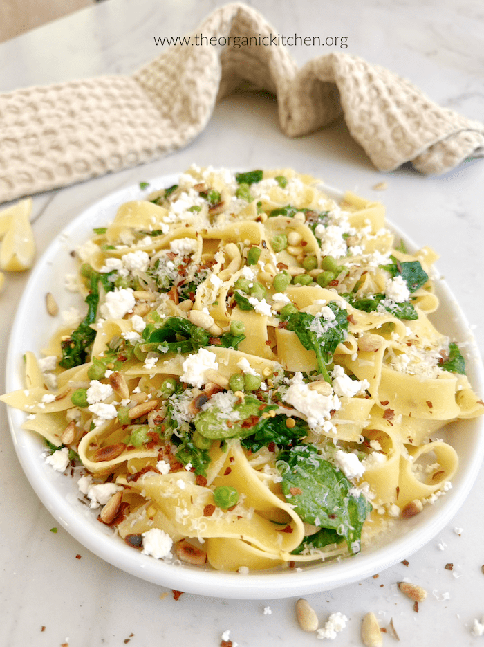 Pappardelle with Wilted Greens (Gluten Free Option) on white plate with beige dish towel in backgrouns
