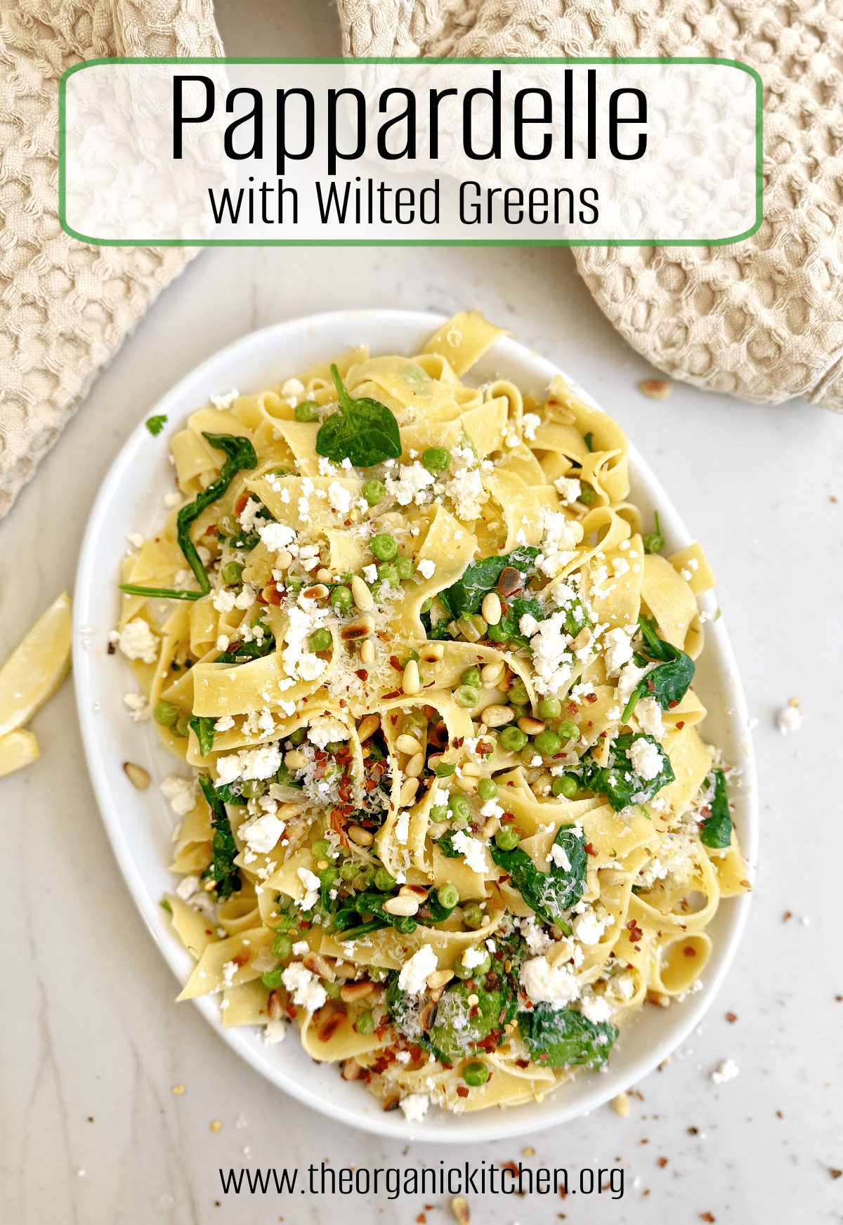 Pappardelle with Wilted Greens (Gluten Free Option) on white plate with beige dish towel above and lemon wedges aside