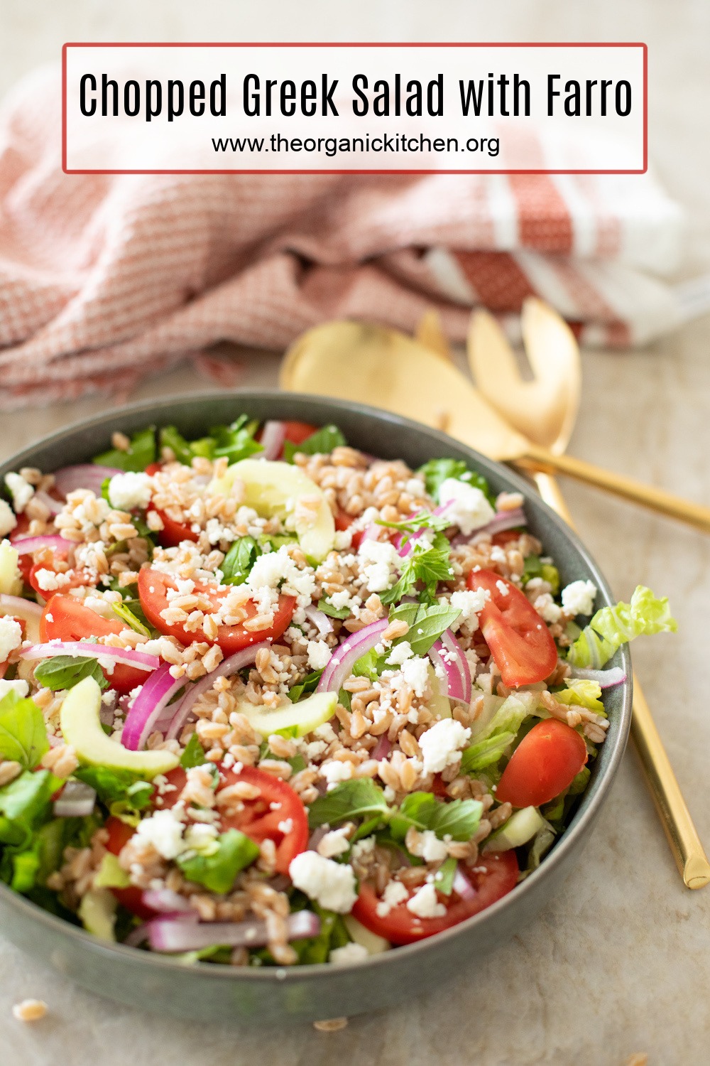 Chopped Greek Salad with Farro in a grey bowl with gold serving spoons