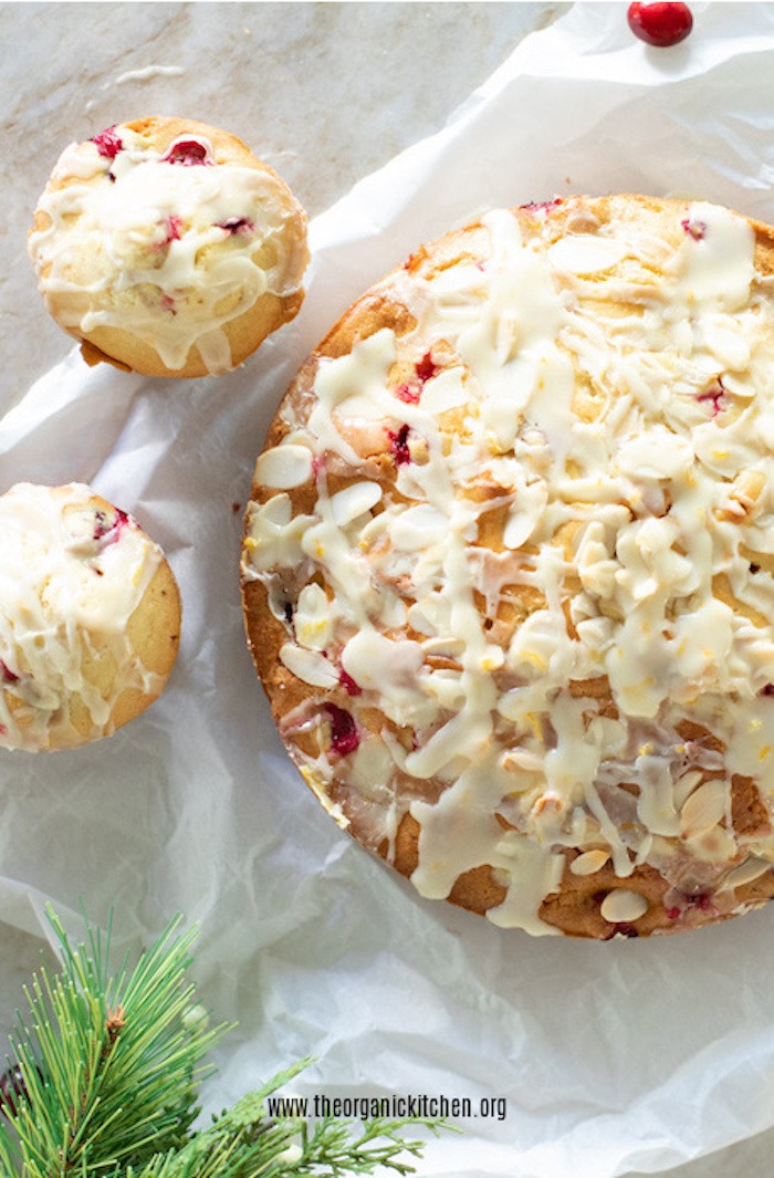 Orange Cranberry Cake and Muffins on white parchment with cranberries