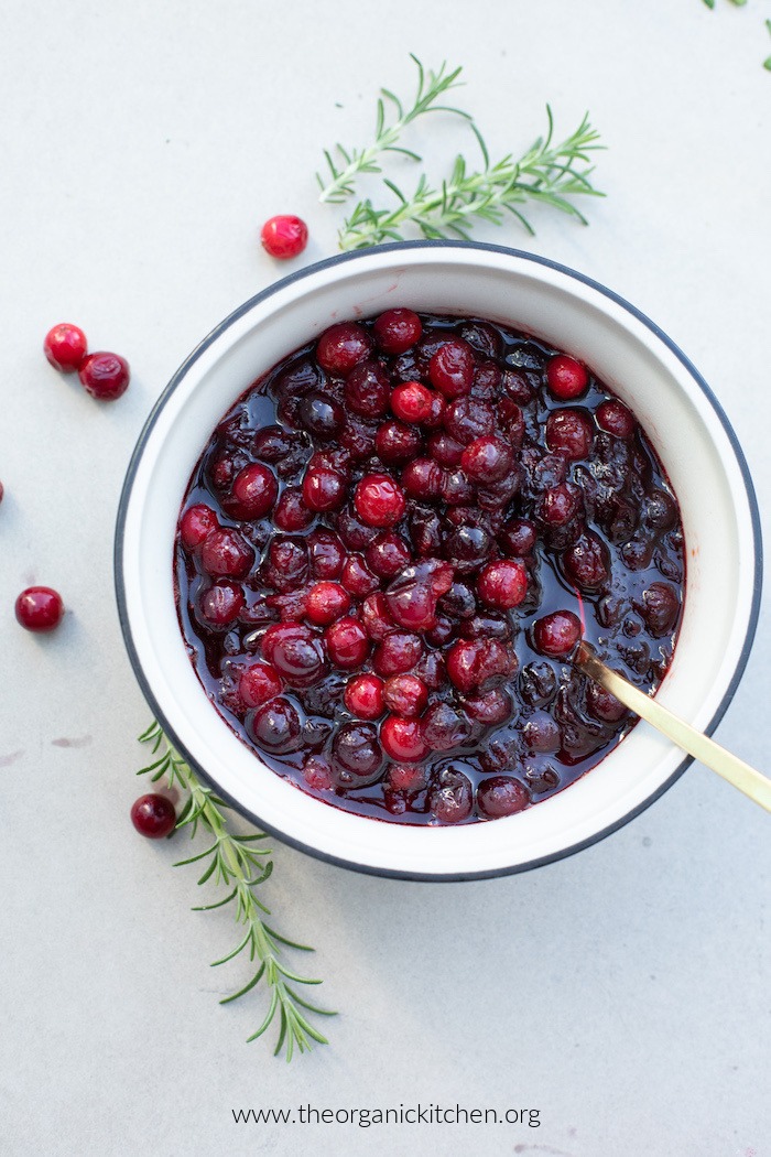 Cranberry sauce in a white bowl garnished with rosemary sprigs