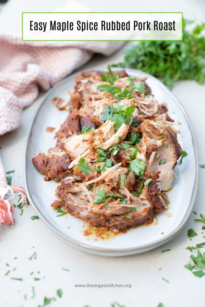 A port roast on a platter with herbs in the background