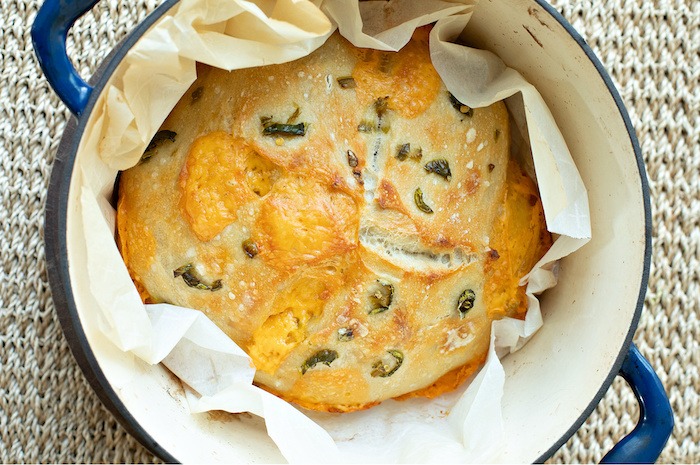 A loaf of freshly baked Cheddar Jalapeno Sourdough in blue Dutch Oven.