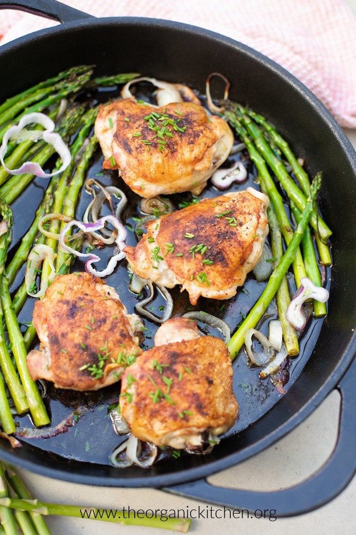 Whole30 One Pan Paprika Chicken and Asparagus in black cast iron pan on cement surface