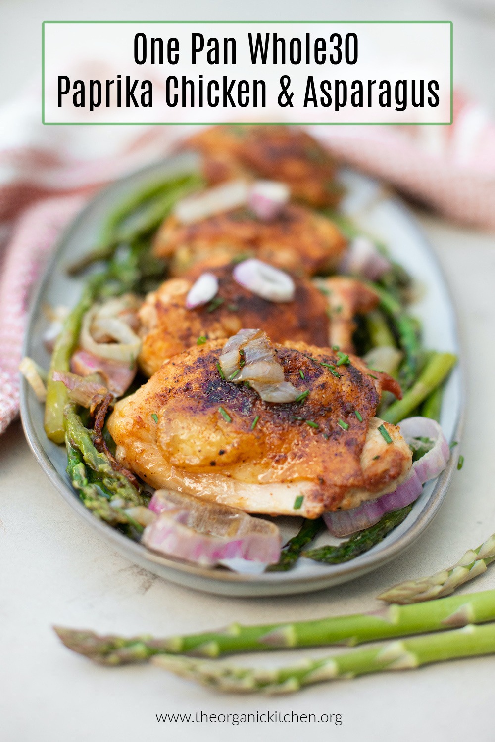 Whole30 One Pan Paprika Chicken and Asparagus garnishes with onions on a gray platter 