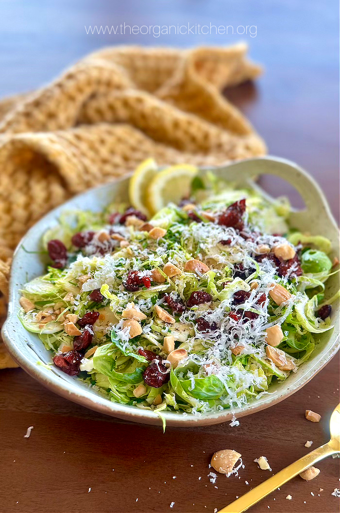 Easy Shaved Brussels Sprouts Salad Easy Shaved Brussels Sprouts Salad garnished with herbs and parmesan in a bowl on wooden table