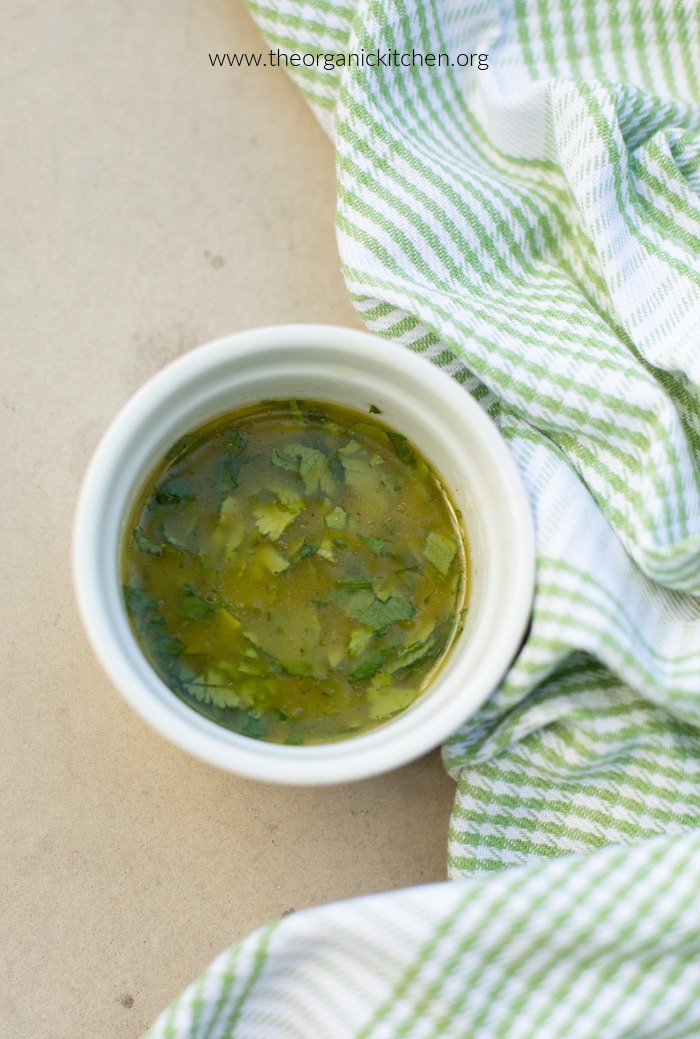 Cilantro Lime Vinaigrette in a white ramekin with a green and white dish towel on the right