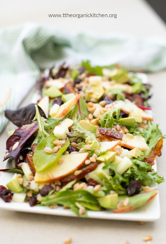 Apple and Farro Salad with chopped dates on white platter with green dish towel in background