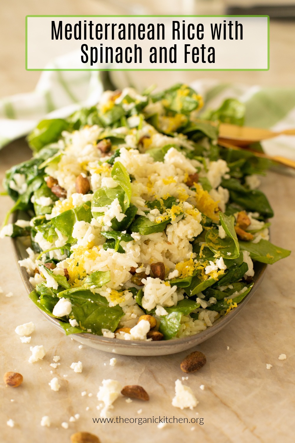Mediterranean Rice with Baby Spinach and Feta garnished with lemon zest on platter with dish towel in background