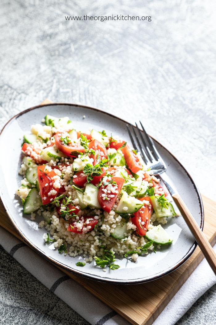 Summer Couscous Salad with tomatoes and cucumbers on gray plate with fork 