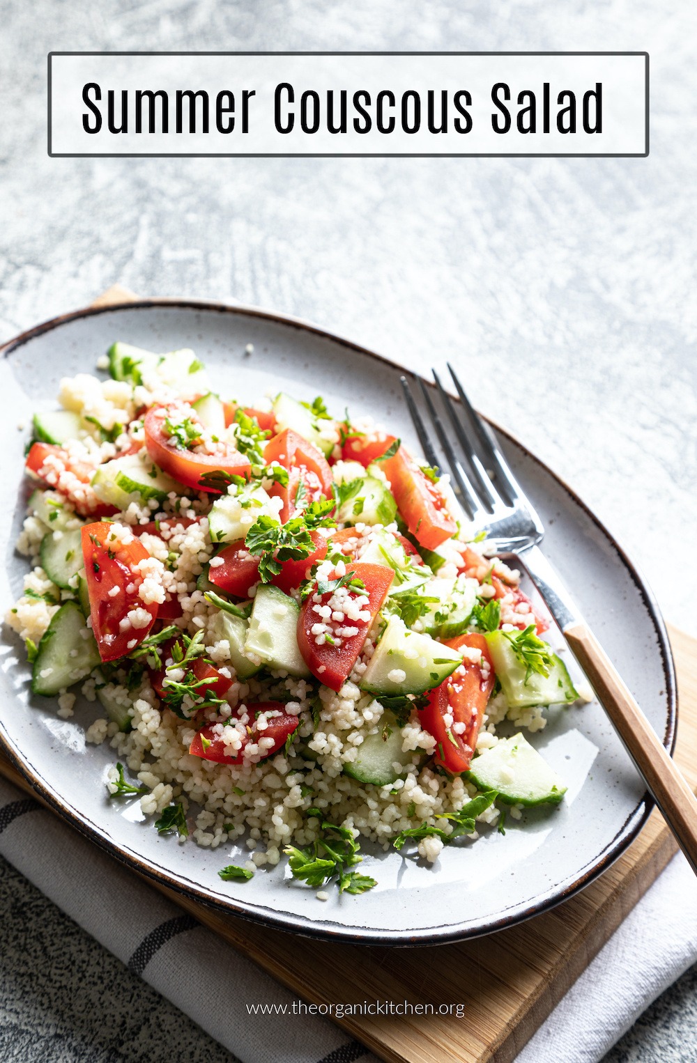 Summer Couscous Salad and fork on gray plate set atop a wood cutting board