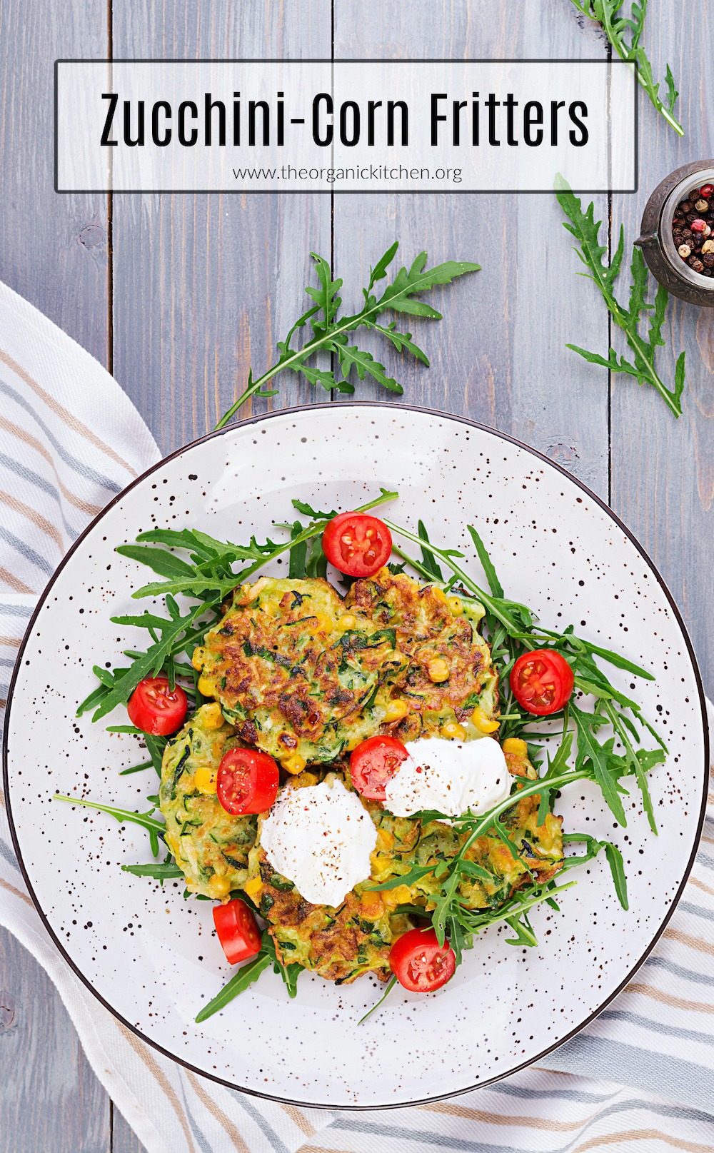 Six Zucchini-Corn Fritters on a black and white speckled plate set on a striped dish towel. 