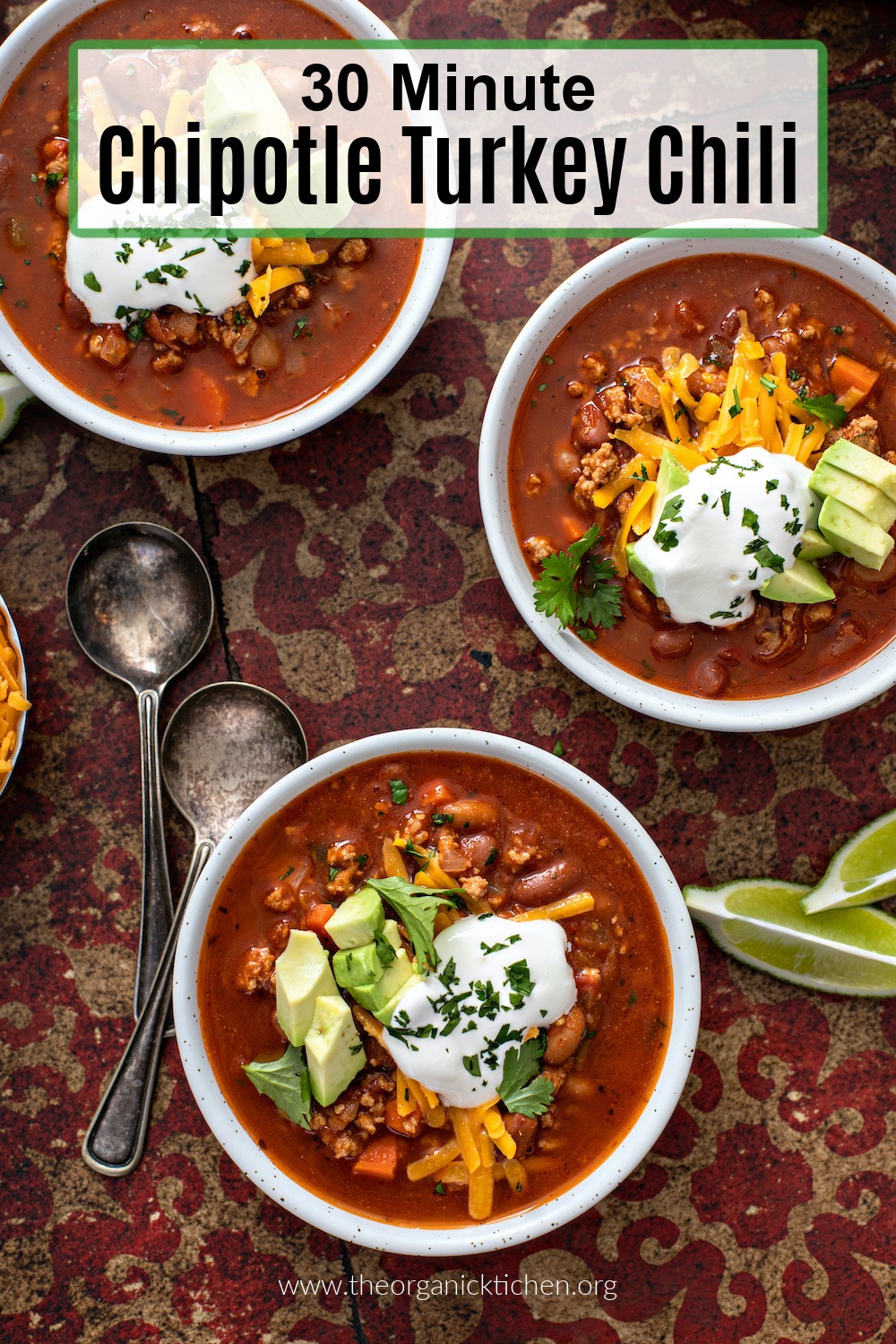 Flat lay of three bowls of 30 minute Chipotle Turkey Chili garnished with cheddar cheese, sour cream and avocado 