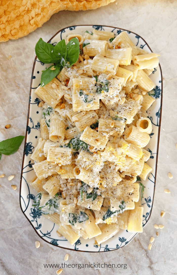 Creamy Lemon Rigatoni with Spinach Creamy Lemon Rigatoni with Spinach garnished with basil and pine nuts on blue and white plate