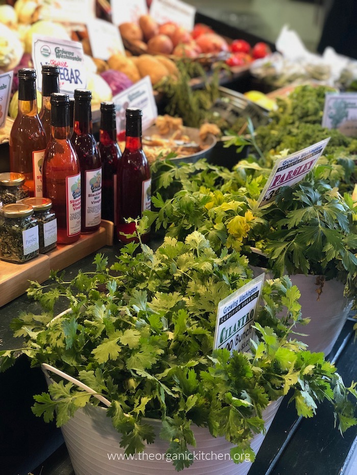 12 Helpful Farmers Market Tips!: Vinrgar bottles, produce and herbs on a farmers market shelf