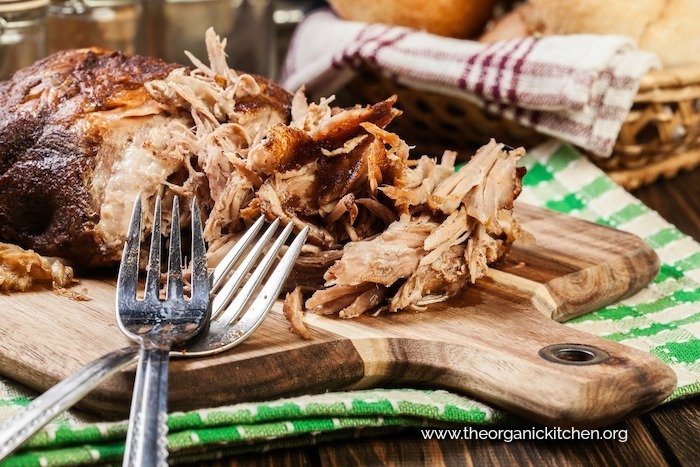 Cooked pork on a wooden platter with two forks for "pulling"