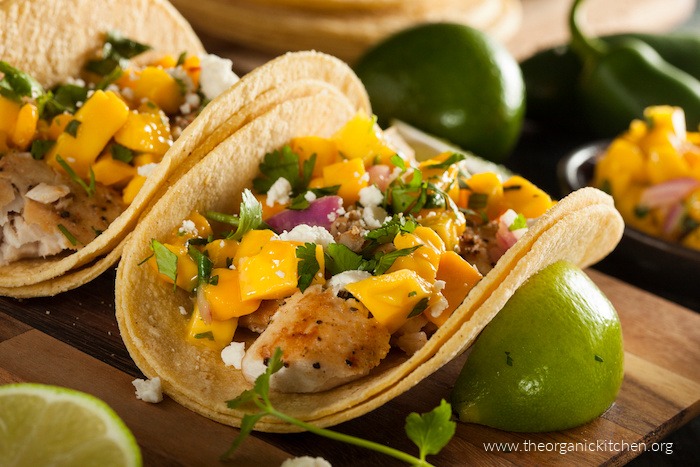 Easy Fish Tacos with Mango Salsa garnished with cheese, red onions, and cilantro