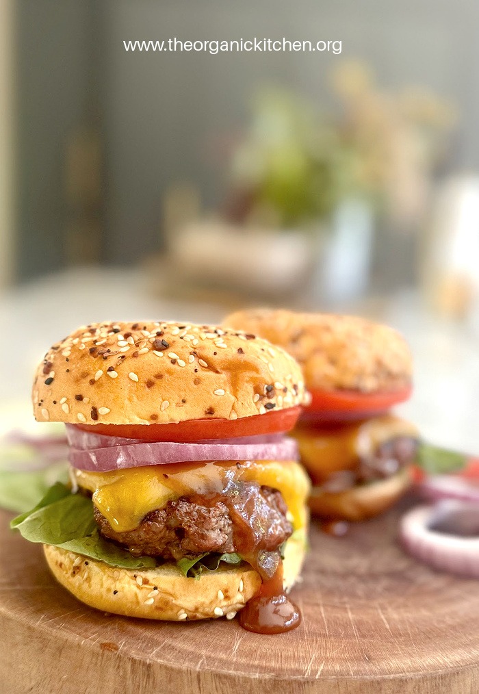Two cheeseburgers on wooden platter with BBQ sauce and melted cheese: How to Make a Fantastic Burger!