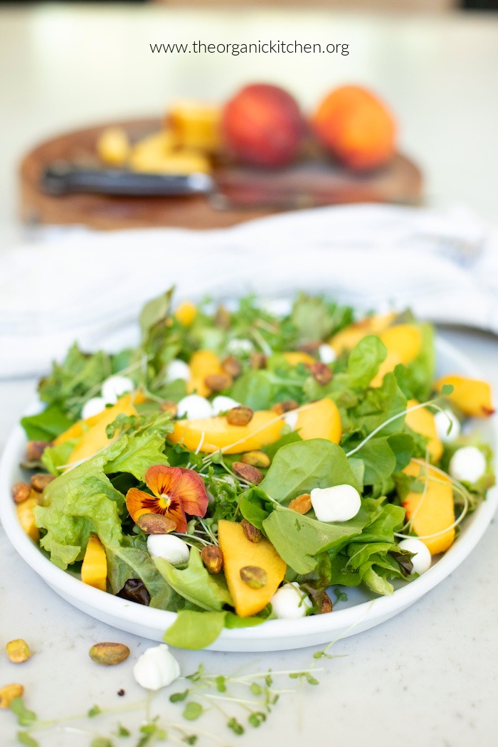 Easy Peach and Mozzarella Salad garnished with micro greens and pistachios on white plate