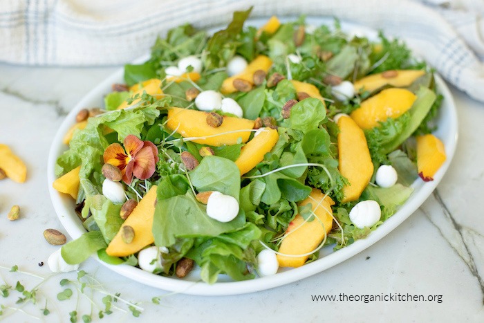 Easy Peach and Mozzarella Salad on white plate set on a white marble surface with blue and white dish towel in background