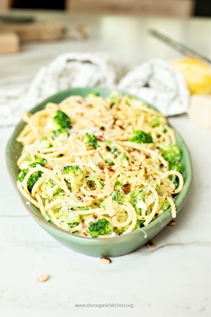 One Pot Pasta with Broccoli and Parmesan on a mint green plate with a dish towel and lemon in the background