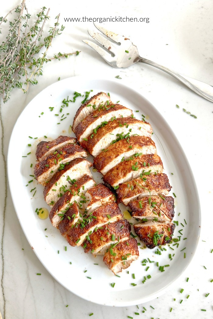 Two Easy Herbed Turkey Tenderloins garnished with chives and thyme sprigs on white plate