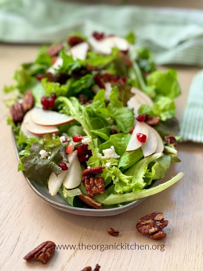 The Pear and Pomegranate Salad garnished with pecans on a gray plate 