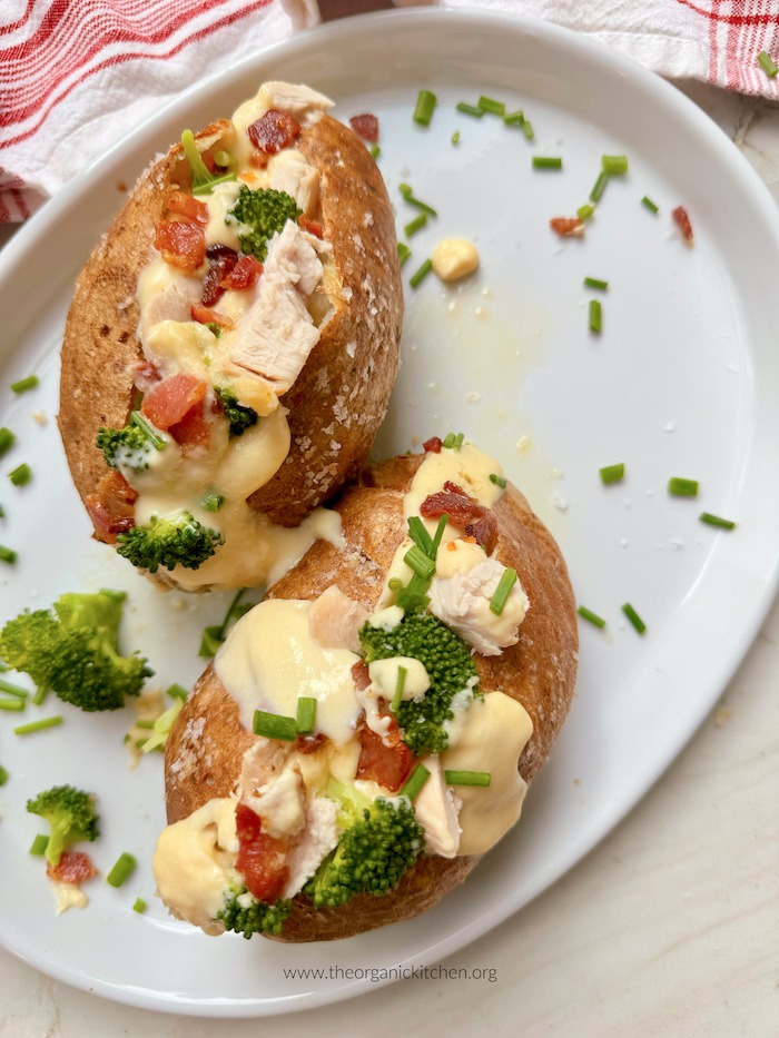 Loaded Baked Potato (aka: Potato Jacket) garnishes with chives on white plate 