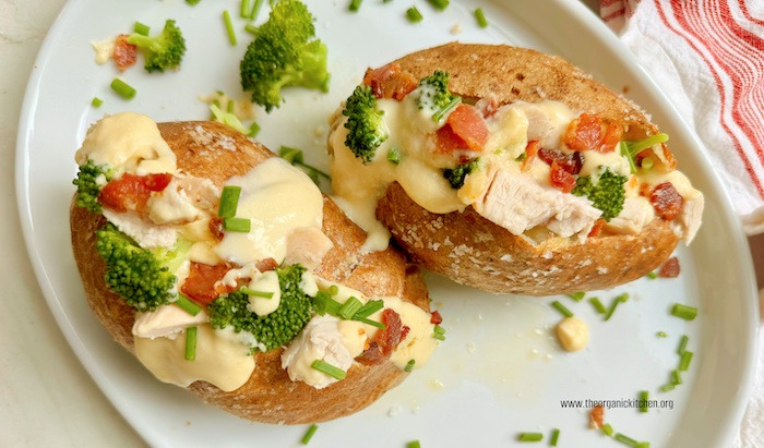 Two loaded baked potatoes on white plate