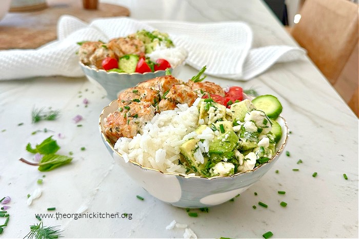 Chicken Meatballs with Avocado and Feta Salad in a gray and white bowl surrounded by herbs