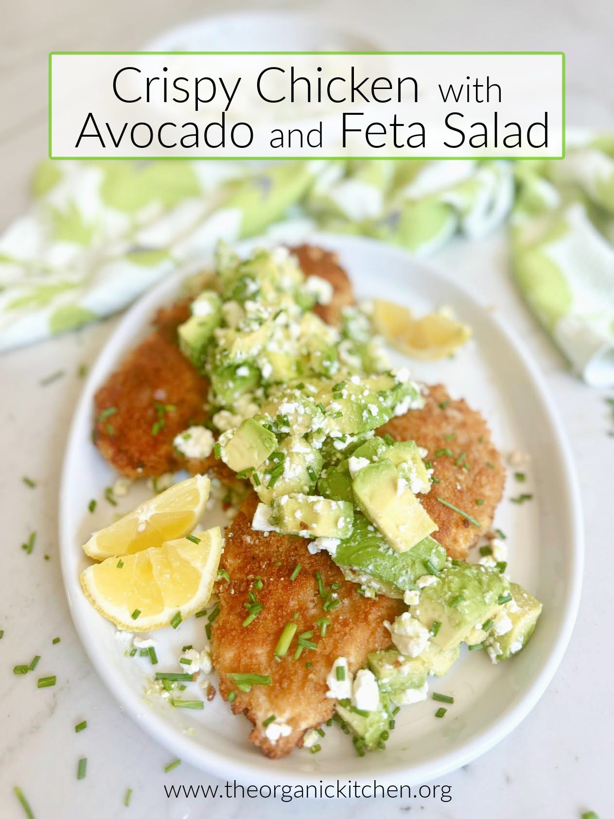 Crispy Chicken with Avocado and Feta Salad Crispy Chicken with Avocado and Feta Salad on white plate garnished with lemon wedges and chivesa