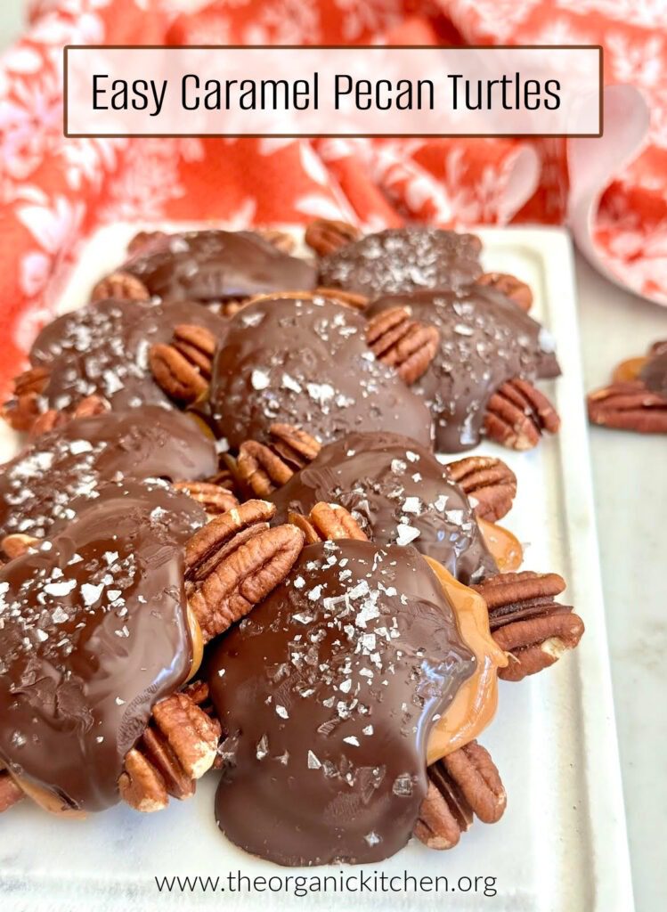 Twelve Delicious Chocolate Desserts! Easy Caramel Pecan Turtles sprinkled with sea salt on a white plate with red dish towel in the background