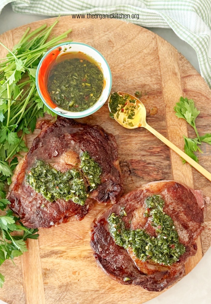 Grilled Rib-Eye Steaks with Chimichurri (Whole30) on wood platter with green and white dish towel in background