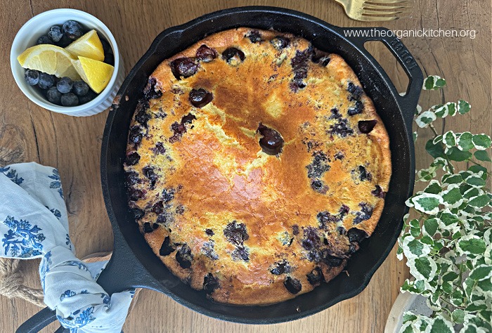 Lemon Blueberry Dutch Baby (No Refined Sugar!) on wood table with a small bowl of lemons and blueberries